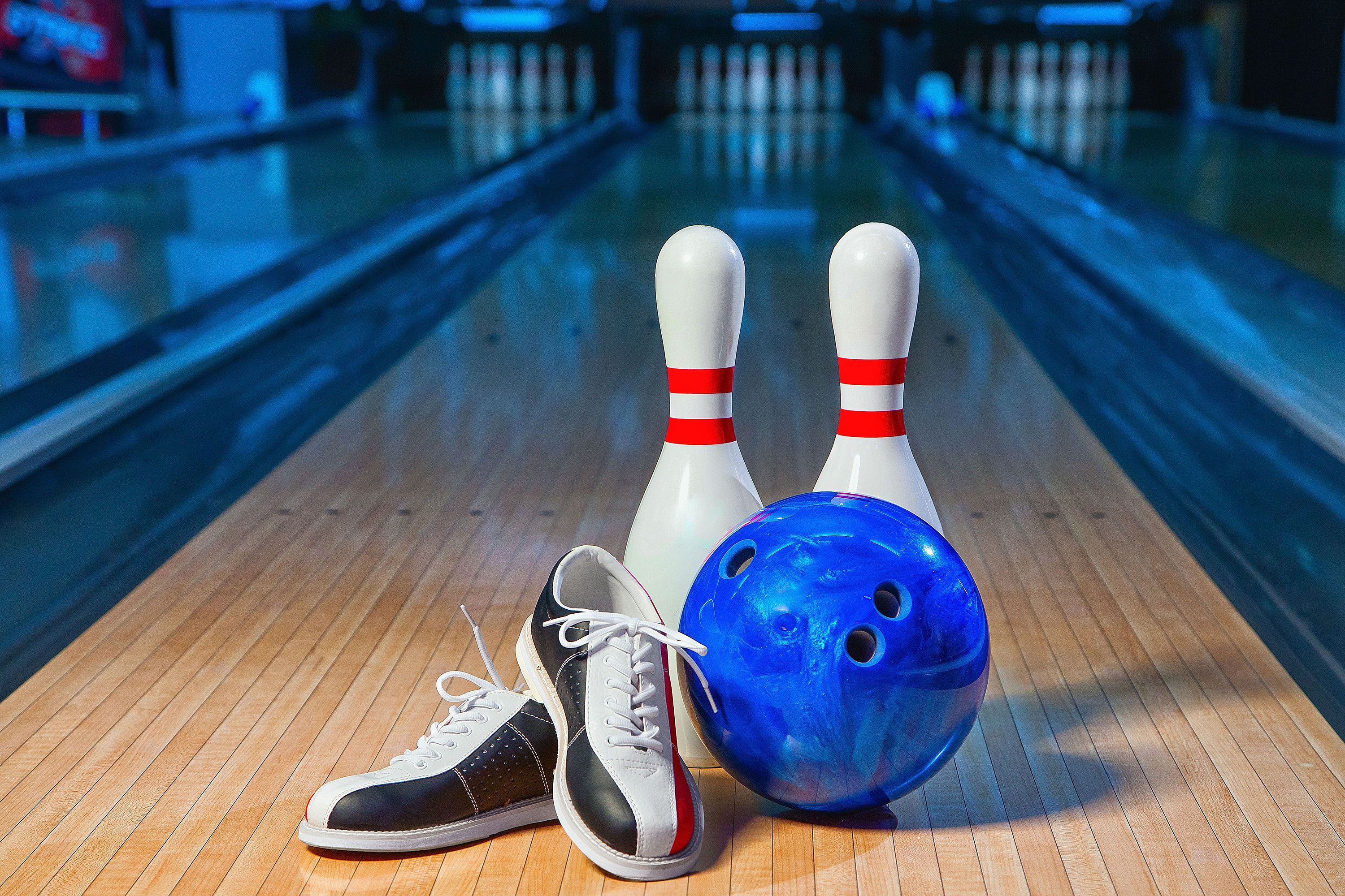 A bowling alley with a wooden floor, two bowling pins, and a blue bowling ball.