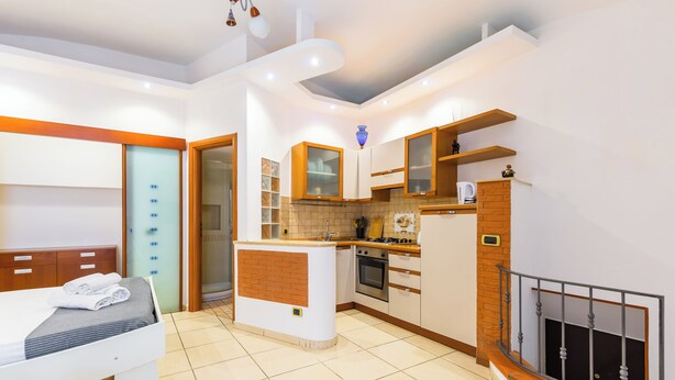 A modern kitchen with a central island, wooden cabinets, and a built-in oven. - Tolentino Studio Flat by Napoliapartments (Naples)