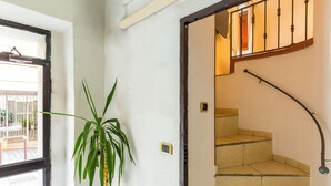 A staircase with a curved handrail and a potted plant beside a door. - Tolentino Studio Flat by Napoliapartments (Naples)