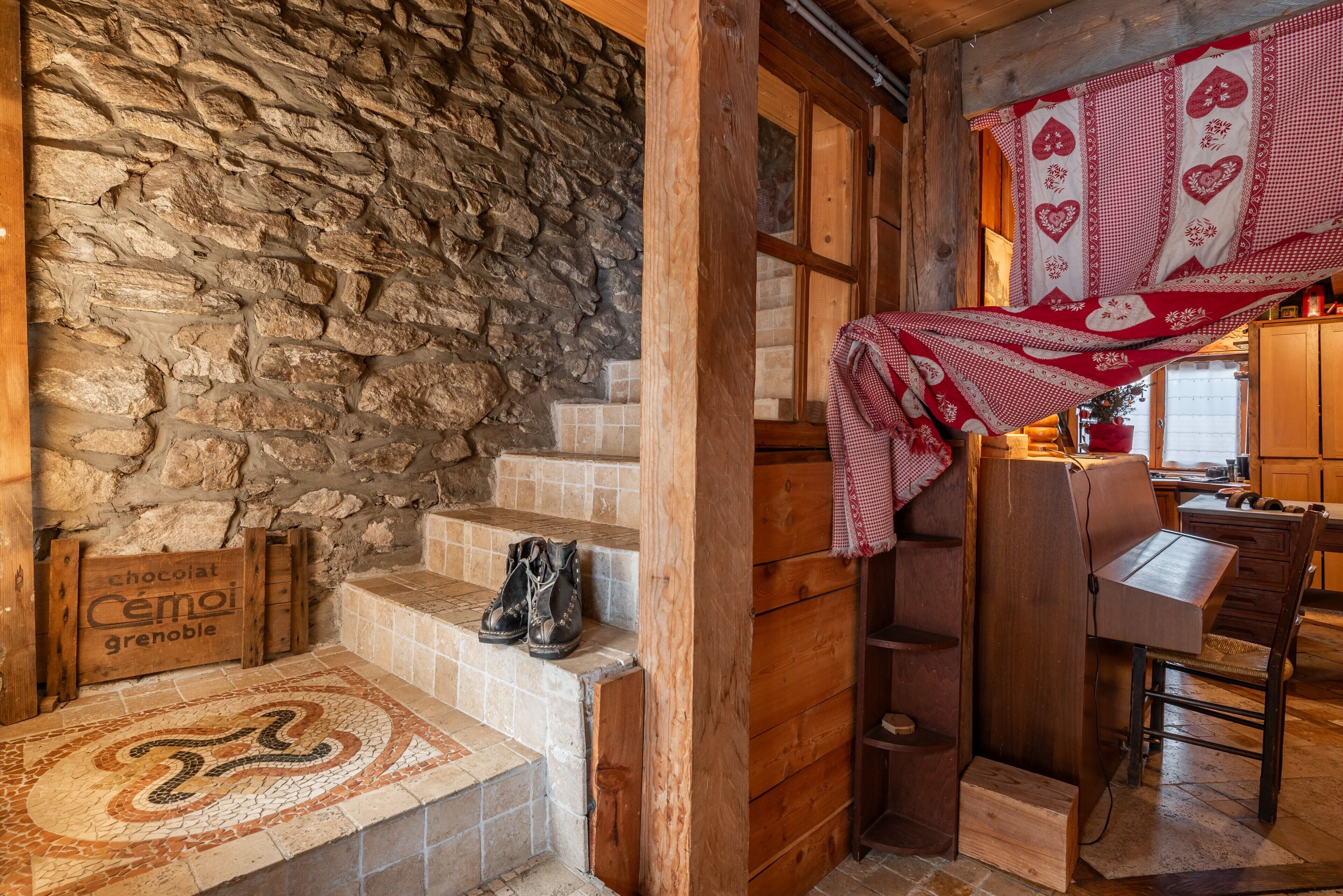 A rustic interior with stone walls, wooden steps, a checkered cloth, and a wooden table.