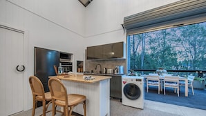 Une cuisine moderne dotée d’un îlot central, d’appareils électroménagers intégrés et offrant une vue sur l’extérieur.