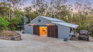 Un bâtiment métallique de plain-pied comprenant un garage, un espace extérieur couvert et un petit jardin.