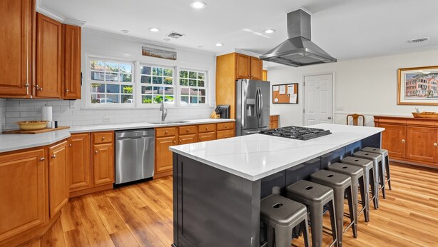 Una cocina moderna con armarios de madera, electrodomésticos de acero inoxidable y una isla grande con taburetes de bar.