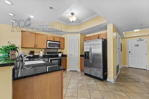Una cocina moderna con armarios de madera, electrodomésticos de acero inoxidable y encimera de granito negro.