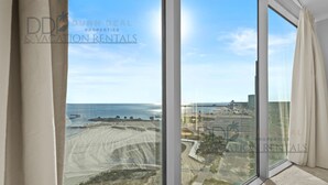 A large window with a view of a beach and a cityscape. - Sea Breeze 907 | Condo Directly on the Beach! (Biloxi)