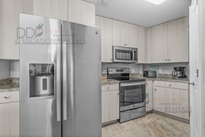 A kitchen with a stainless steel refrigerator, a microwave, an oven, and a coffee maker.