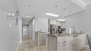A modern kitchen with granite countertops, stainless steel appliances, and a central island. - Sea Breeze 907 | Condo Directly on the Beach! (Biloxi)
