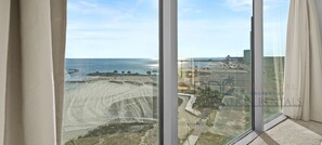 A large window with a view of a beach and a cityscape.