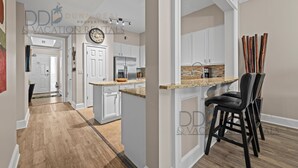 A modern kitchen with white cabinets, a stainless steel refrigerator, and a granite countertop. - Legacy Tower I 1403 | Penthouse Unit Overlooking the Beautiful Gulf! (Gulfport)