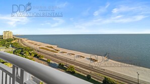A coastal view with a beach, road, and buildings. - Legacy Tower I 1403 | Penthouse Unit Overlooking the Beautiful Gulf! (Gulfport)