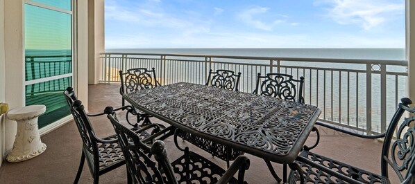 A balcony with a table and chairs, overlooking a body of water.