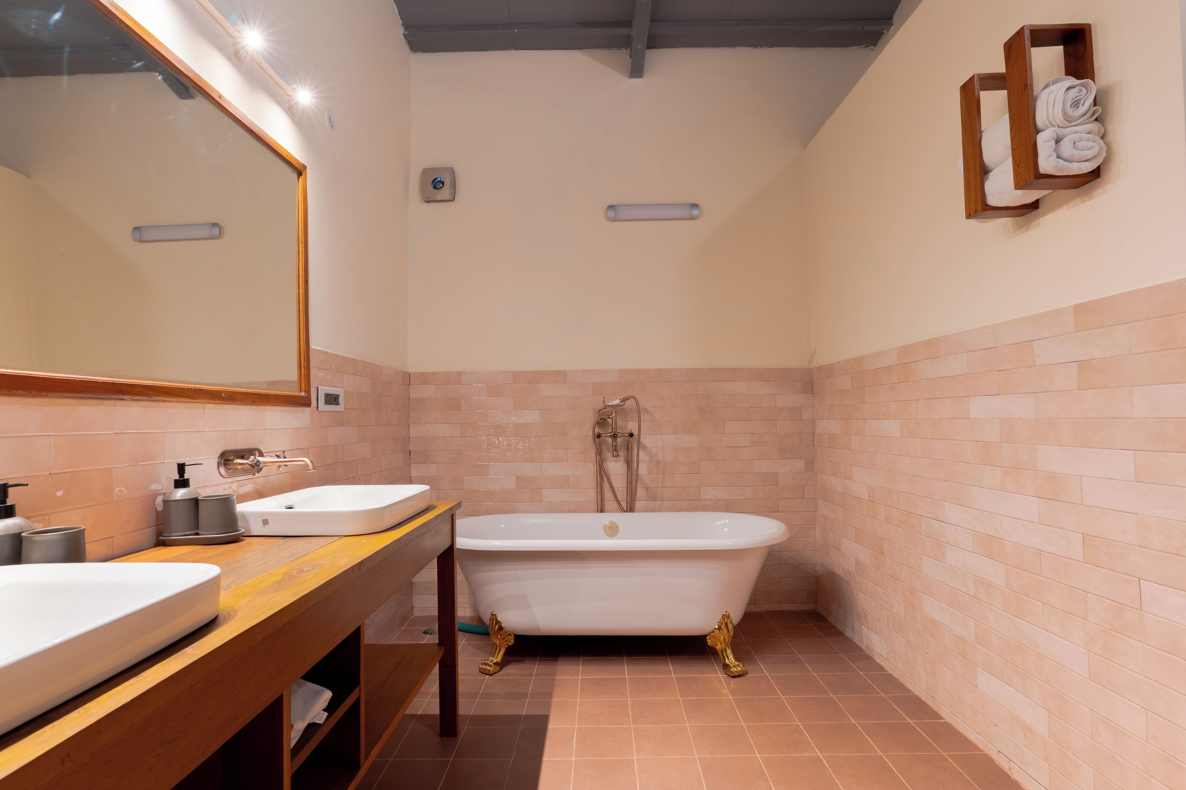 A bathroom with a freestanding bathtub, a vanity with a mirror, and a towel rack on the wall.