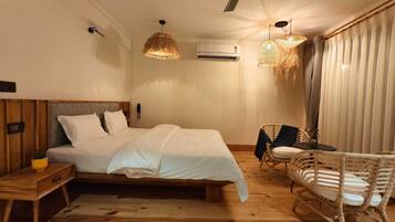 A bedroom with a bed, bedside tables, a ceiling fan, and a wicker chair.