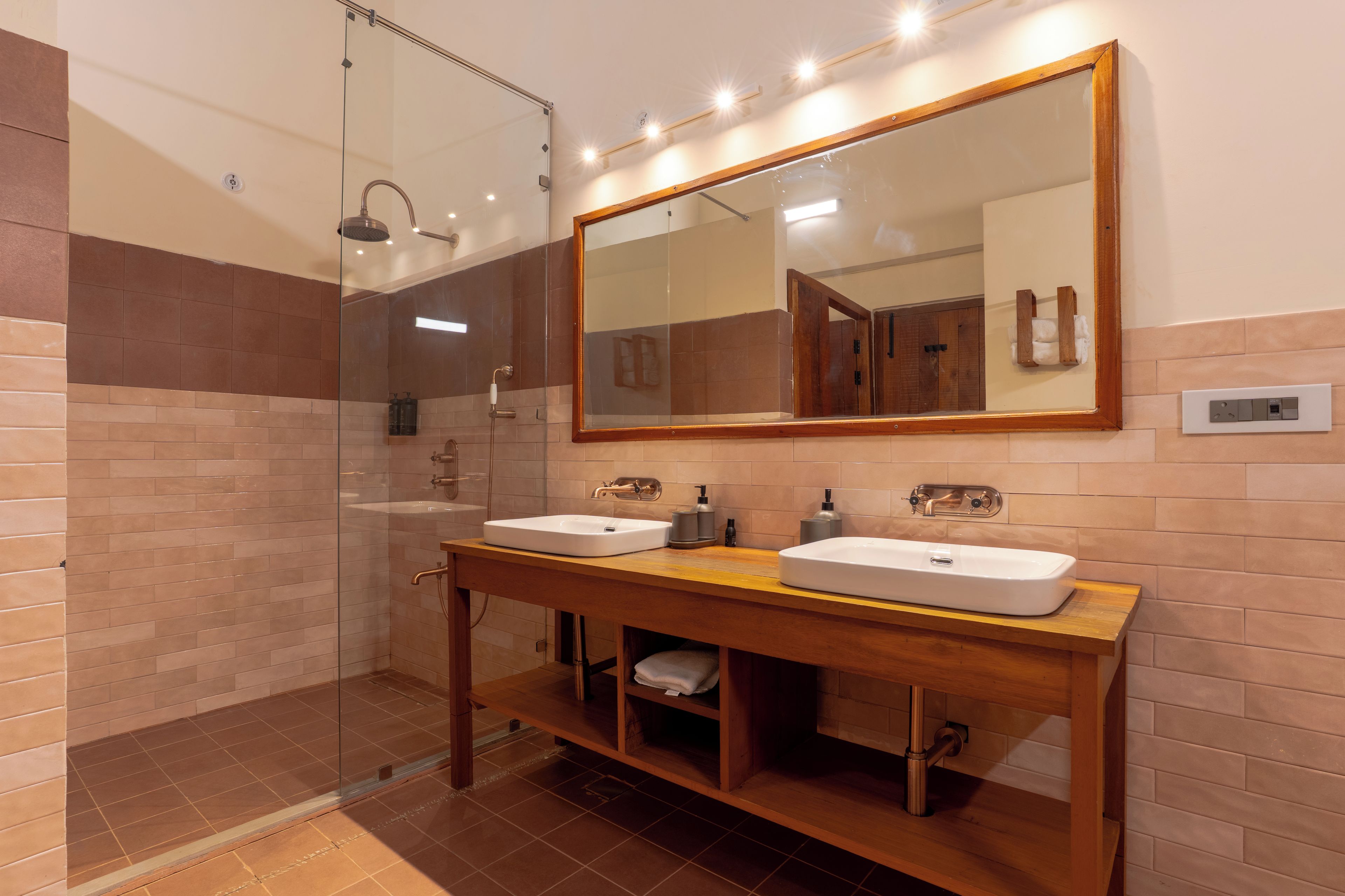 A modern bathroom with two sinks, a glass shower enclosure, and a large mirror.