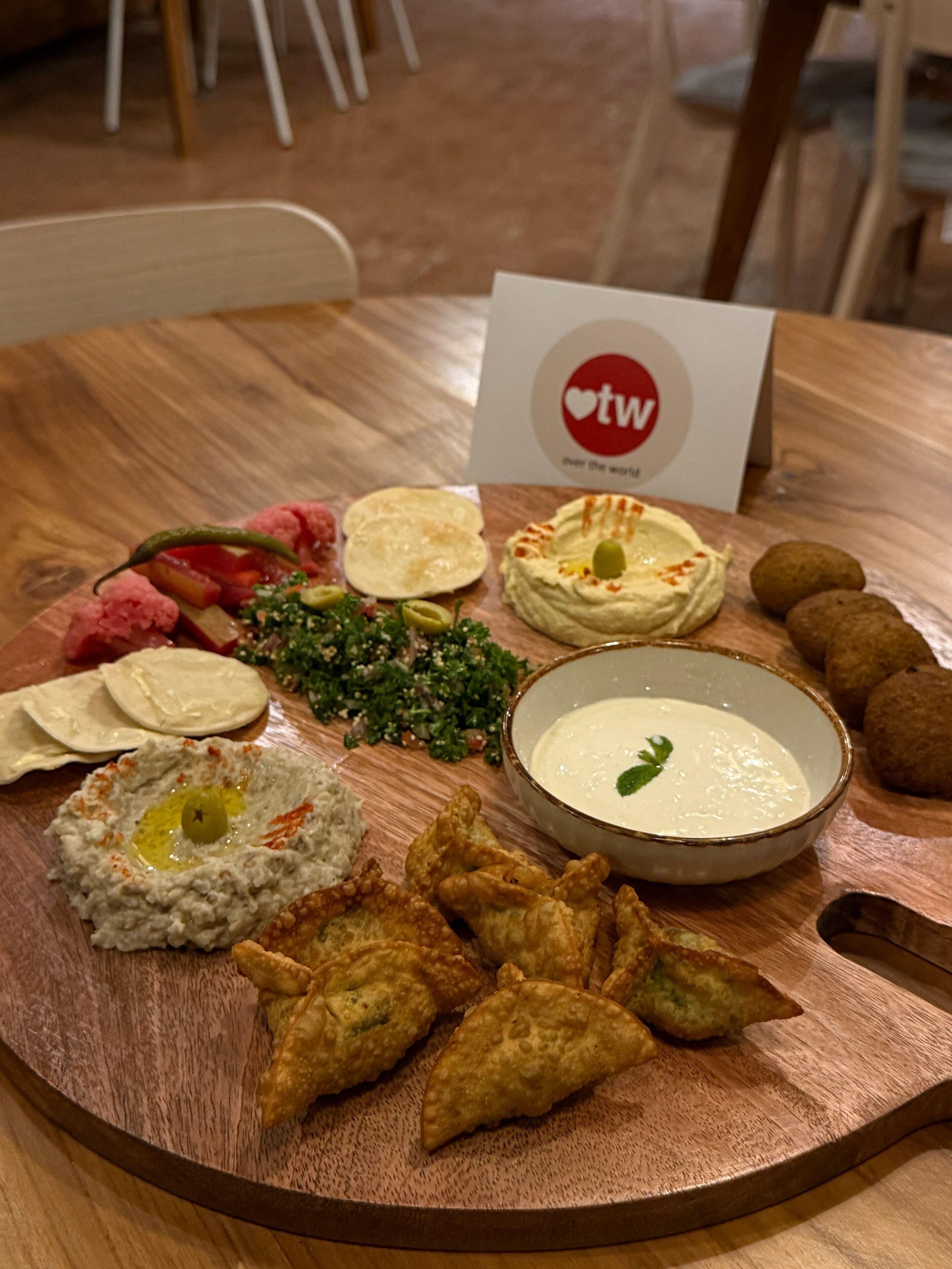 A wooden table with a variety of food items including hummus, pita bread, and falafel.