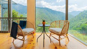 A balcony with wicker chairs, a small round table, and a potted plant. - Over The World (Kosiyakutoli)