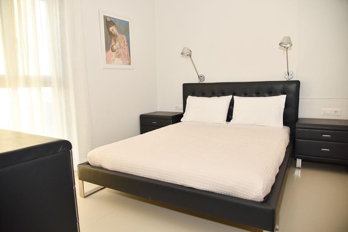 Une chambre à coucher bien rangée, avec un lit, des tables de chevet et un tableau accroché au mur.