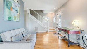 Ein geräumiges Wohnzimmer mit einem weißen Sofa, einer Treppe und einem Tisch mit einer Lampe.