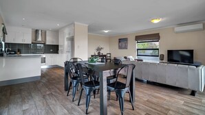 A modern kitchen with a dining area, a sofa, and a TV. - Long Island Retreat: Pelican. The Perfect Riverside Family Getaway. (Murray Bridge)