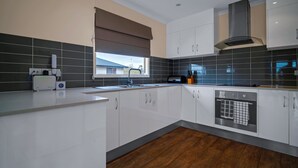A modern kitchen with white cabinets, a built-in oven, and a window with a view. - Long Island Retreat: Pelican. The Perfect Riverside Family Getaway. (Murray Bridge)