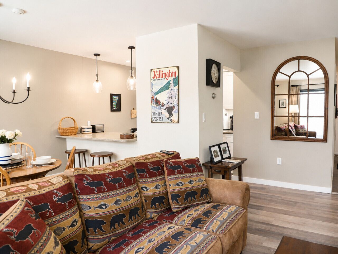 A living room with a sofa, dining table, chandelier, and a poster on the wall.