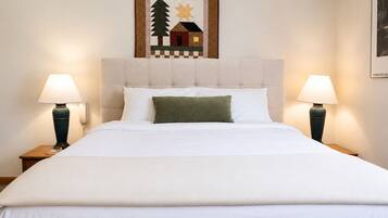 A bed with a white duvet, two bedside lamps, and a framed picture above it.