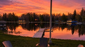 Um cenário à beira do lago com lareira e cadeiras Adirondack.