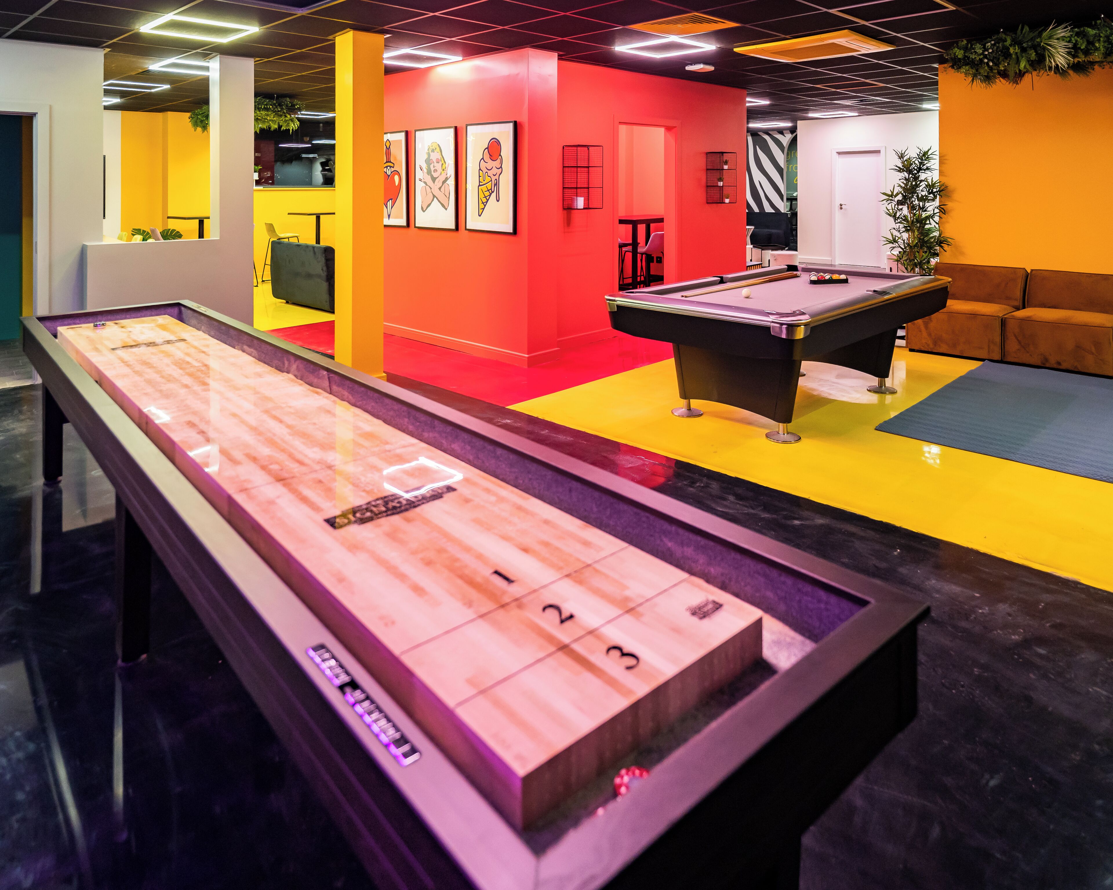 Une table de billard dans une pièce aux couleurs vives, avec un mur rouge et un sol jaune.