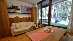 Une pièce chaleureuse avec une table en bois, un canapé et une fenêtre donnant sur une forêt.