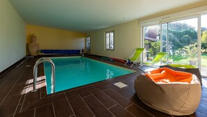 Ein Hallenbad mit freiem Blick ins Freie, eine blaue Bank und ein Sitzsack.