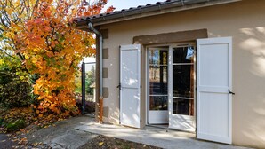Ein Gebäude mit beiger Fassade, einem Betonweg und einem Baum mit Herbstlaub.