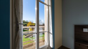 Ein Zimmer mit einem großen Fenster, einer Holztür und Blick auf einen Garten und eine Brücke.