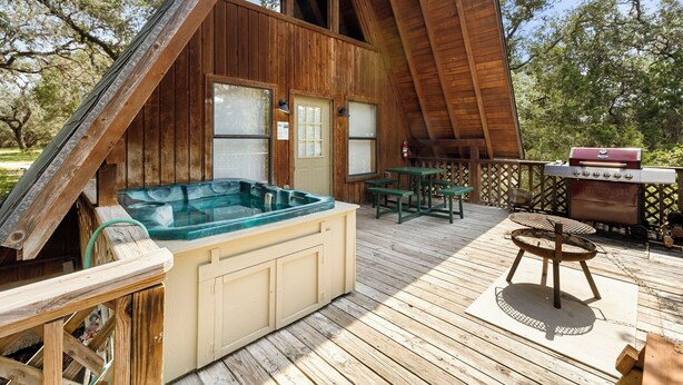 Eine Holzterrasse mit Whirlpool, Grill und Tisch.