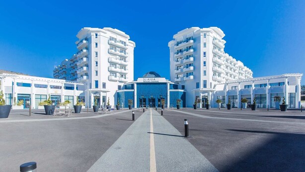 A modern hotel with a central atrium, multiple floors, and a clear sky.