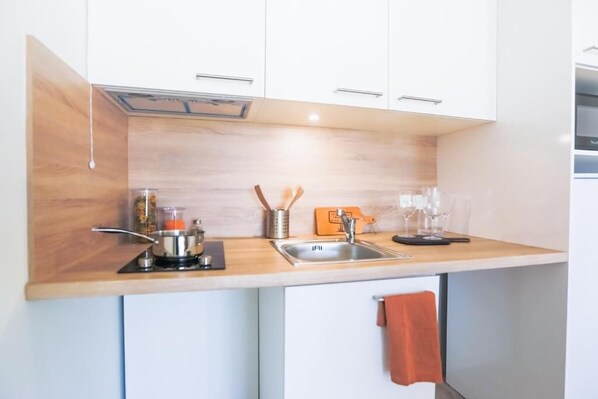 Una cocina moderna con armarios blancos, una encimera de madera, un lavabo y diferentes utensilios de cocina.