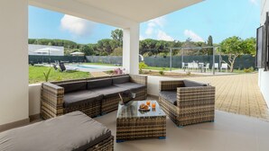 A covered outdoor seating area with wicker furniture, a pool, and a view of the surrounding greenery. - Villa 'Giovanna' with Private Pool, Wi-Fi and Air Conditioning (sorso)