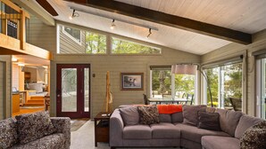 A spacious living area with a large sectional sofa, a small table, and a staircase leading to an upper level. - Lakeside Escape | 5BR | Hot Tub | Family Friendly (Traverse City)
