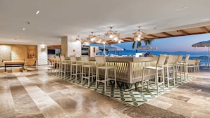 Een ruime eethoek binnen met een lange tafel en stoelen, een bar en uitzicht op de oceaan.