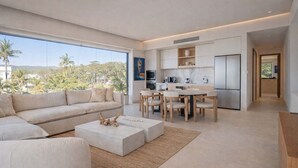 Een moderne woonkamer met een bank, salontafel en eethoek.