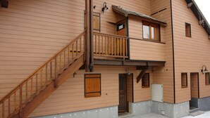 A two-story building with a wooden staircase, multiple windows, and a balcony.
