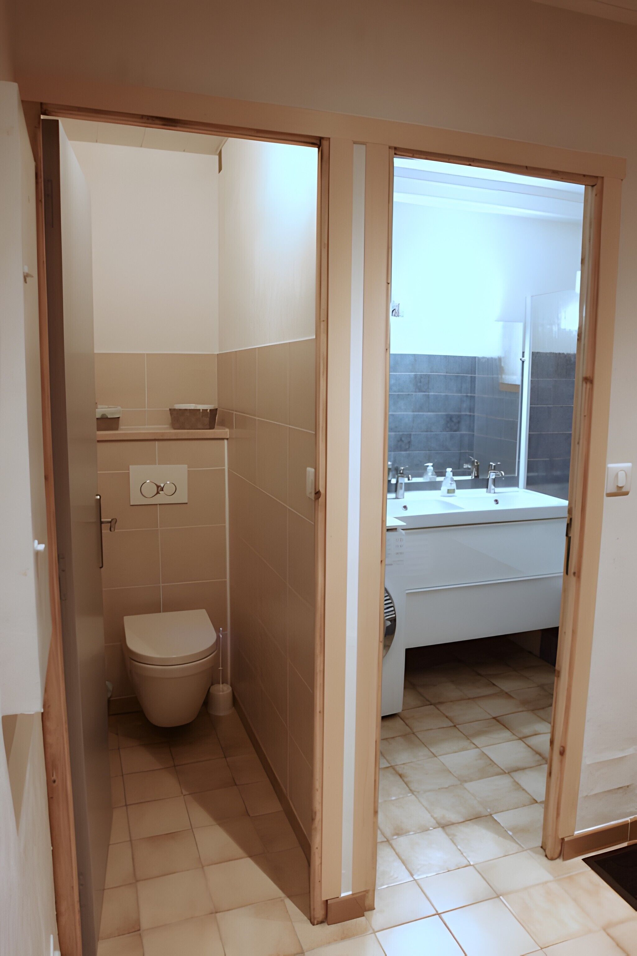 A bathroom with a toilet, sink, and mirror.