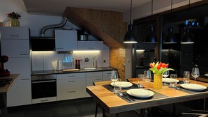 Una cucina moderna con un tavolo da pranzo in legno apparecchiato per quattro persone, completo di piatti, bicchieri e posate.