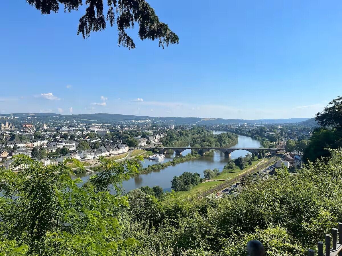 A river with a bridge, surrounded by greenery and buildings.