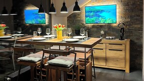 Una cucina moderna con una grande isola, illuminazione a sospensione e una parete decorata con pietra.