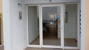 A building entrance with a glass door, a sign above indicating 'Edificio Varandas Vila Mar', and a number '91' on the wall.