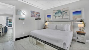 Une chambre à coucher moderne avec un grand lit, une table de chevet avec une lampe et des œuvres d’art accrochées aux murs.