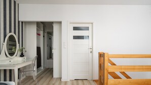 A bedroom with a wooden bed, a white door, a mirror, and a desk with a chair. - AS HOME Kościuszki 89 (Wrocław)
