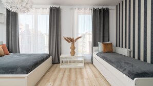A modern bedroom with a bed, a bench, and a window with curtains. - AS HOME Kościuszki 89 (Wrocław)