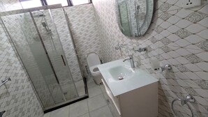 A bathroom with a glass shower enclosure, a toilet, and a sink with a mirror above it. - ITUNDA NICE RESIDENCE KIGALI (Kigali)