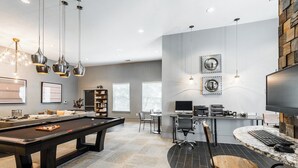 A modern living room with a pool table, a comfortable seating area, a dining table with chairs, and a workspace with a computer and desk.